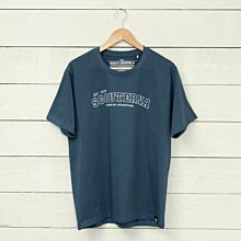 Blå T-shirt scouterna 1910 hängandes på galge mot vägg